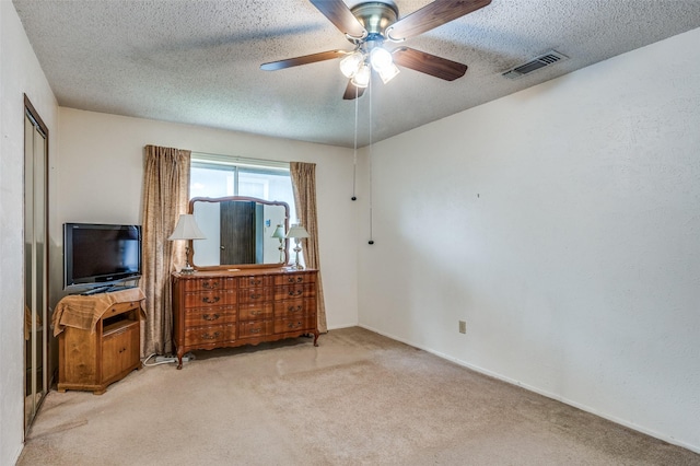 carpeted bedroom with a textured ceiling, ceiling fan, and visible vents