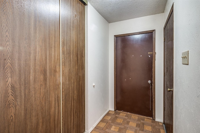 hall featuring a textured ceiling and baseboards