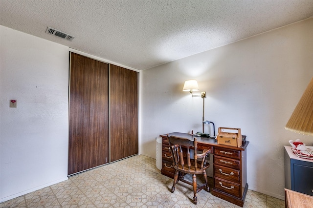 office with light floors, baseboards, visible vents, and a textured ceiling