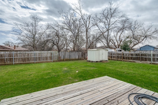 deck featuring a yard, a fenced backyard, an outdoor structure, and a storage shed