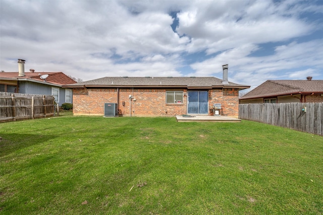 back of house with a yard, brick siding, and a fenced backyard