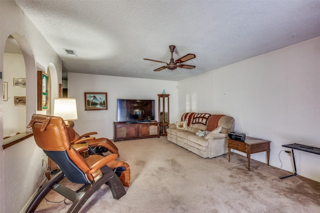 living area with arched walkways, carpet, visible vents, a ceiling fan, and a textured ceiling