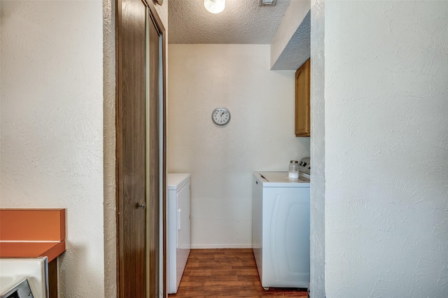 laundry area featuring cabinet space, dark wood finished floors, a textured wall, a textured ceiling, and washer and dryer