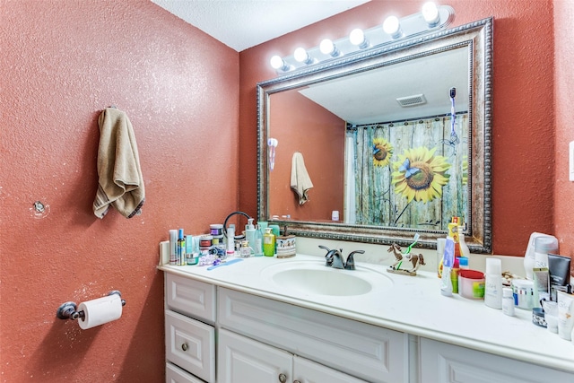 full bathroom featuring visible vents, a textured wall, and vanity