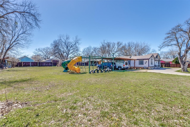 view of yard with driveway, fence, and playground community