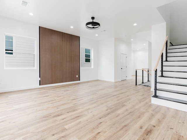 unfurnished living room with visible vents, baseboards, stairs, light wood-type flooring, and recessed lighting