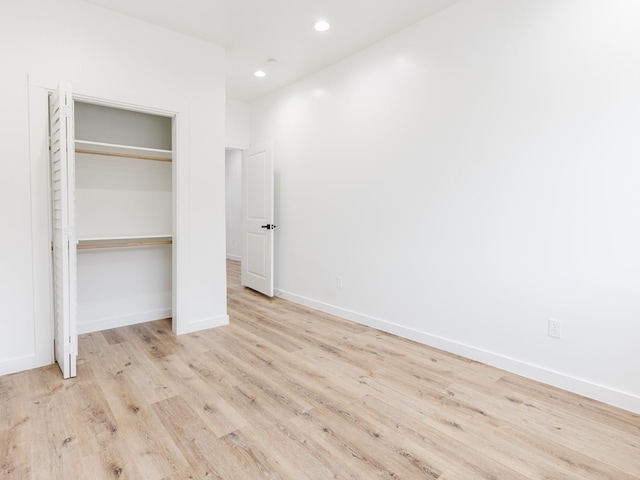 unfurnished bedroom with a closet, recessed lighting, baseboards, and wood finished floors