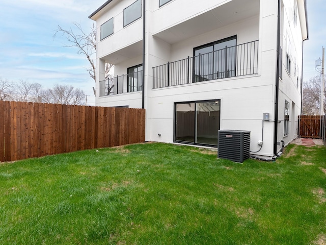 back of house featuring a yard, central AC unit, stucco siding, and fence