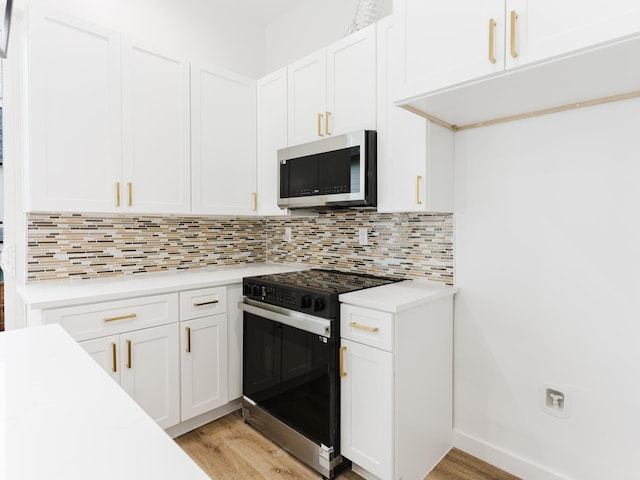 kitchen with black / electric stove, light countertops, white cabinetry, stainless steel microwave, and tasteful backsplash