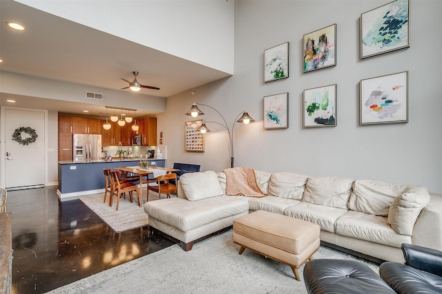 living area with recessed lighting, visible vents, finished concrete floors, a ceiling fan, and baseboards