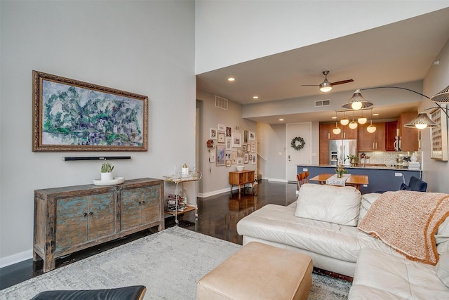 living area with baseboards, visible vents, ceiling fan, and wood finished floors