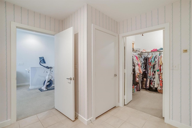 hall with light tile patterned flooring, light colored carpet, and wallpapered walls