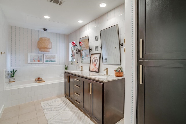 bathroom with double vanity, visible vents, tile patterned floors, a garden tub, and a sink