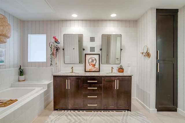 bathroom with double vanity, a garden tub, a sink, and tile patterned floors