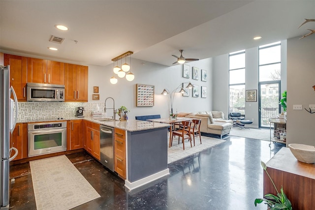 kitchen featuring visible vents, appliances with stainless steel finishes, open floor plan, a peninsula, and a sink