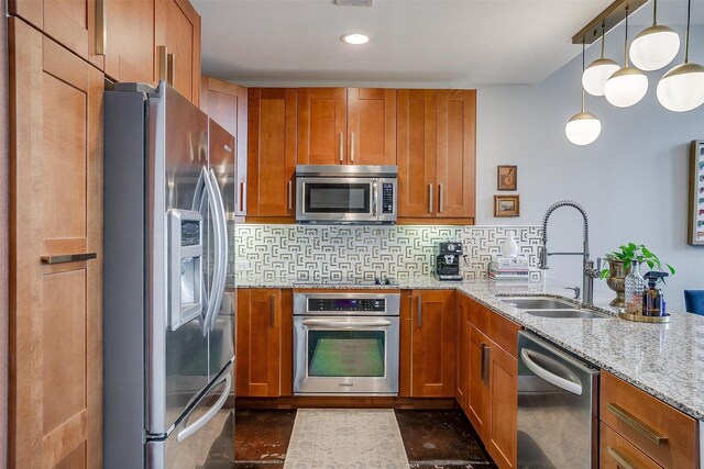 kitchen featuring stainless steel appliances, brown cabinetry, a sink, and backsplash