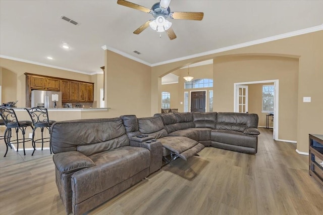 living room with light wood-style flooring, visible vents, arched walkways, and baseboards