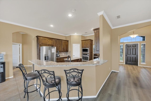 kitchen with arched walkways, stainless steel appliances, visible vents, baseboards, and crown molding