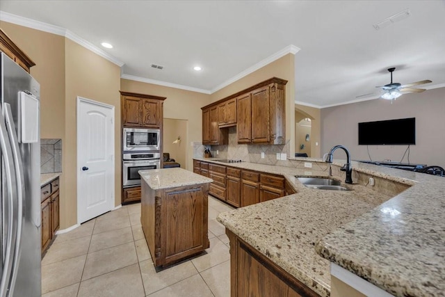 kitchen with arched walkways, tasteful backsplash, visible vents, appliances with stainless steel finishes, and a sink