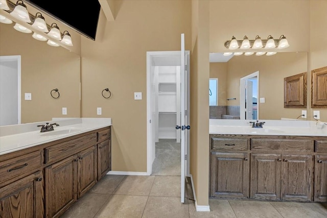 full bathroom with baseboards, a sink, tile patterned flooring, a walk in closet, and two vanities