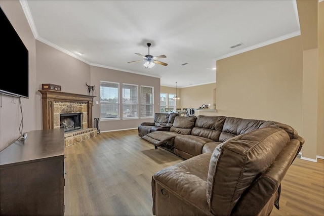 living area with a tiled fireplace, light wood-type flooring, baseboards, and crown molding