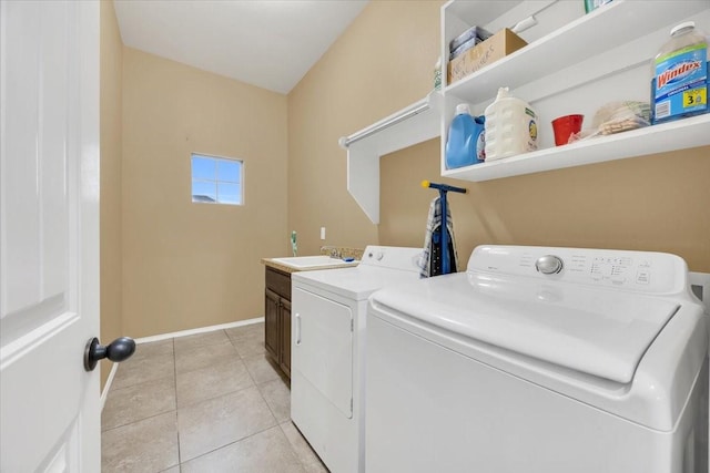 washroom with washer and clothes dryer, cabinet space, light tile patterned flooring, a sink, and baseboards