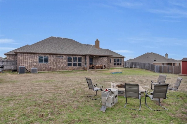 rear view of house featuring a yard, brick siding, central AC, and fence