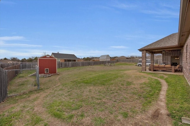 view of yard with a patio area, a fenced backyard, an outdoor structure, and a storage unit