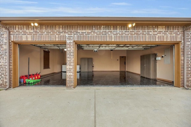 exterior space with a garage, a patio, brick siding, and electric panel