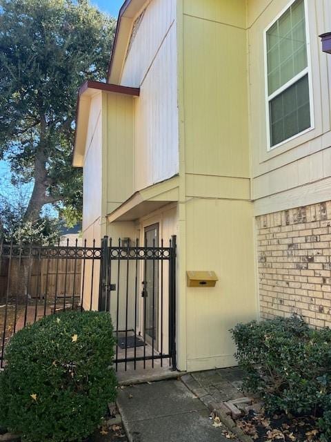 exterior space with a gate, brick siding, and fence