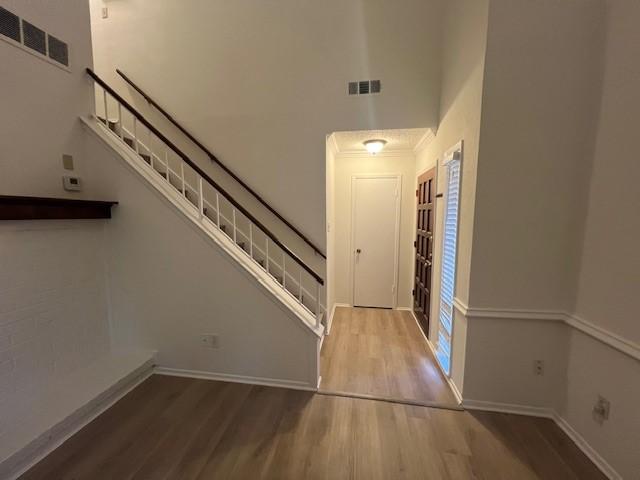 foyer entrance featuring wood finished floors, a towering ceiling, and visible vents