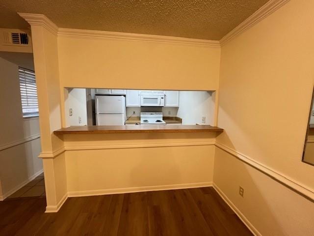 kitchen with a textured ceiling, white appliances, dark wood-type flooring, and crown molding