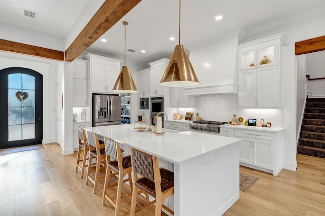 kitchen featuring visible vents, light wood-style flooring, custom exhaust hood, stainless steel appliances, and beam ceiling