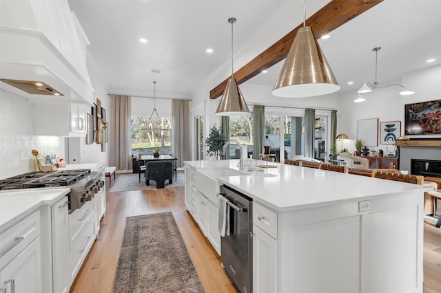 kitchen featuring stainless steel appliances, a sink, open floor plan, backsplash, and custom range hood