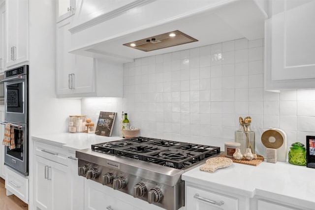 kitchen with stainless steel appliances, light countertops, white cabinets, and decorative backsplash