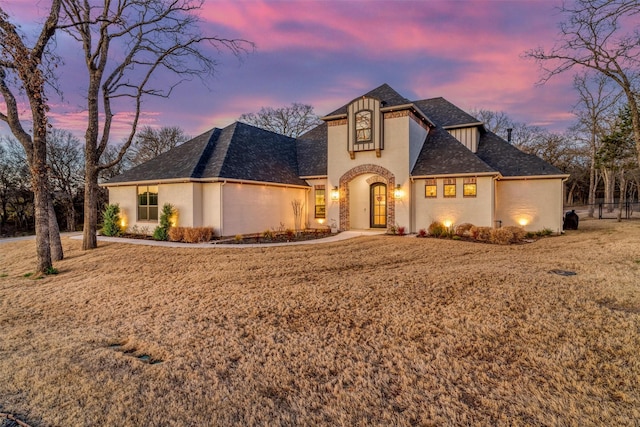 french country home featuring roof with shingles