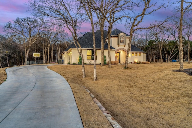 french provincial home featuring driveway and stucco siding