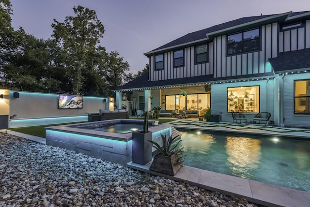 rear view of property featuring board and batten siding, an in ground hot tub, an outdoor pool, and an outdoor hangout area