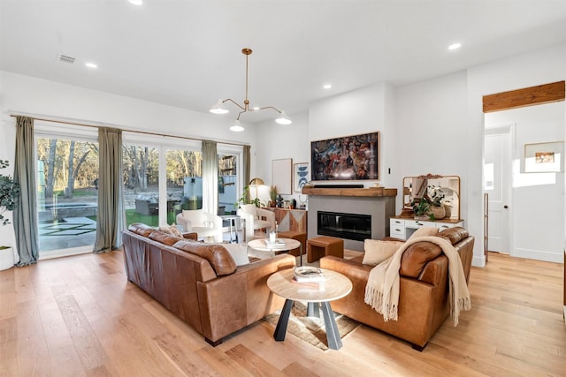 living area featuring light wood-style floors, recessed lighting, and a glass covered fireplace