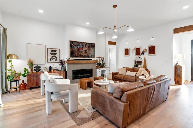 living area featuring light wood-type flooring, a glass covered fireplace, and recessed lighting