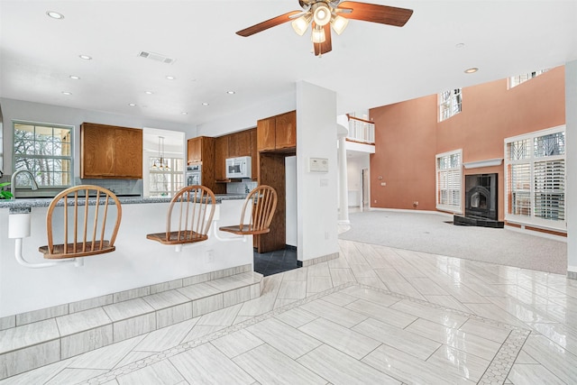 kitchen featuring oven, visible vents, white microwave, and brown cabinetry