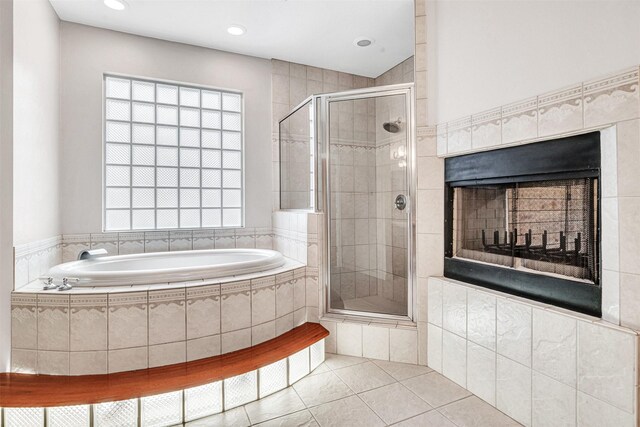 bathroom featuring tile patterned floors, a bath, a stall shower, and a tile fireplace