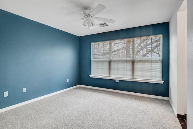 carpeted empty room with visible vents, baseboards, and a ceiling fan