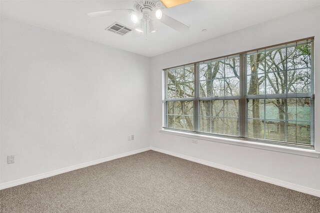 carpeted empty room with baseboards, visible vents, and ceiling fan