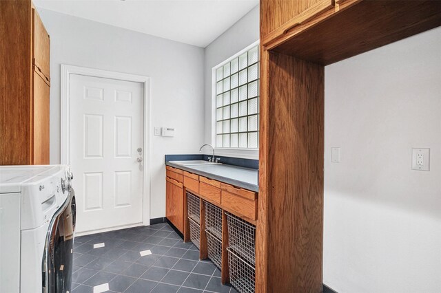 laundry area with baseboards, washer and clothes dryer, dark tile patterned floors, cabinet space, and a sink