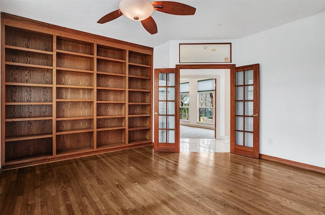 empty room featuring french doors, baseboards, a ceiling fan, and wood finished floors