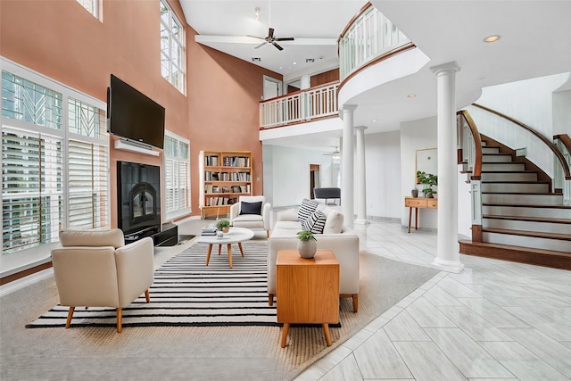 tiled living room with stairway, a fireplace, a ceiling fan, and ornate columns