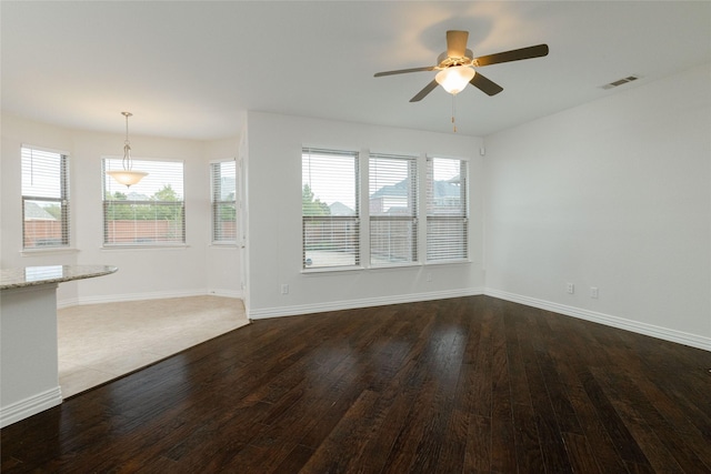 unfurnished living room with a ceiling fan, dark wood-style floors, visible vents, and baseboards