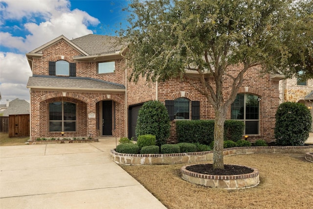 traditional-style home featuring brick siding, driveway, and roof with shingles