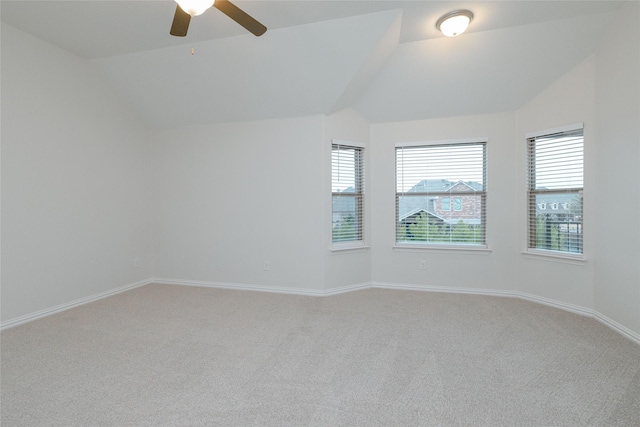 spare room featuring lofted ceiling, a healthy amount of sunlight, and light carpet